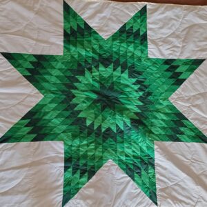Green star quilt pattern on white fabric.