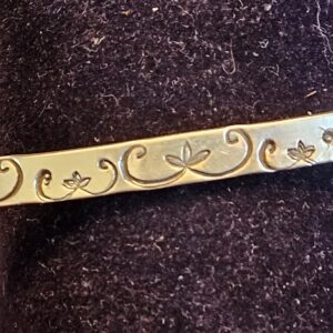 Gold bracelet with engraved floral design.
