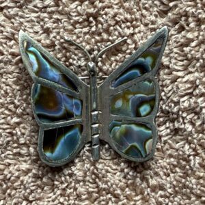 Butterfly brooch with colorful inlay on fabric.