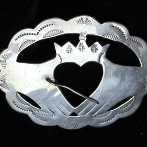 Silver brooch with heart and crown design.