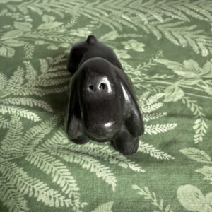 Black ceramic dog on green patterned fabric.