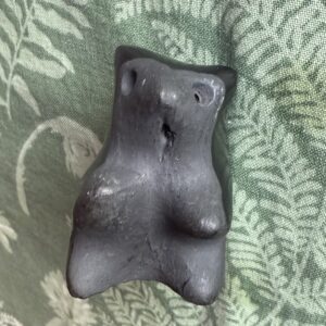 Black clay bear sculpture on patterned fabric.