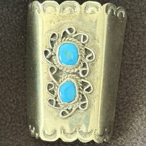 Ornate silver ring with two turquoise stones and intricate designs.
